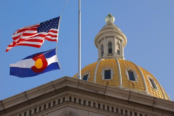 The Denver Capital building dome next to an American and Colorado State flag.