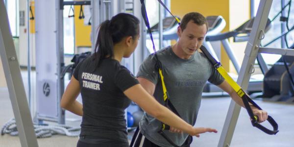 Personal trainer working with client on TRX ropes