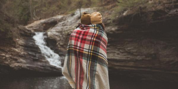 Couple under a blanket by a stream