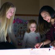 Researcher and children smiling at light table