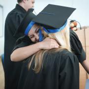 High school graduates hugging at graduation ceremony