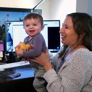 Mom holding baby with laptop in background