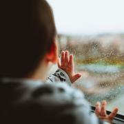 Baby touching rain spotted window