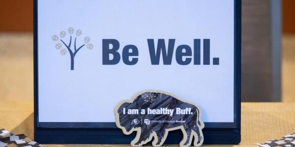 A Be Well sign on a table at a CU Boulder event.