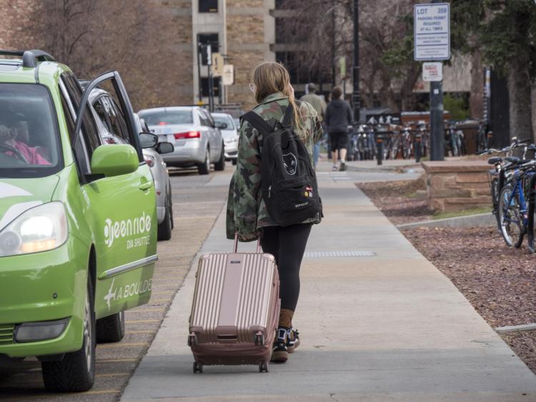 Student leaving campus with suitcase