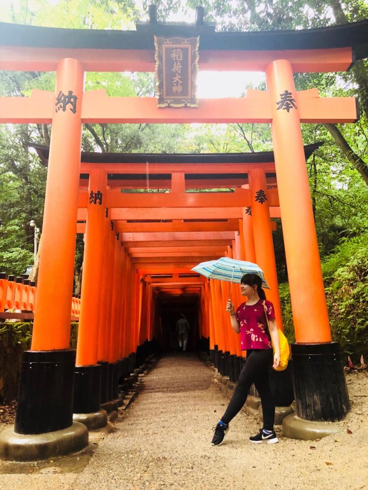 Student poses under traditional Japanese arches in Tokyo