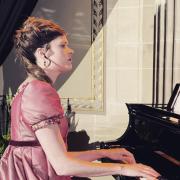 Laura Klein dressed in Regency clothes and playing piano