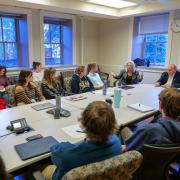 A Community Scholars Program cohort meets at a conference table. 