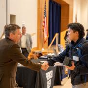 Student shakes hands with an employer at a campus career fair