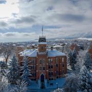 A snow-dusted Old Main and campus grounds against a sunny blue sky.