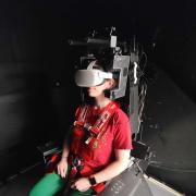 Woman sits strapped into heavy-duty chair wearing a virtual reality headset